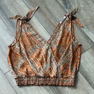 Lightweight and breezy cropped blouse featuring adjustable tie shoulders.